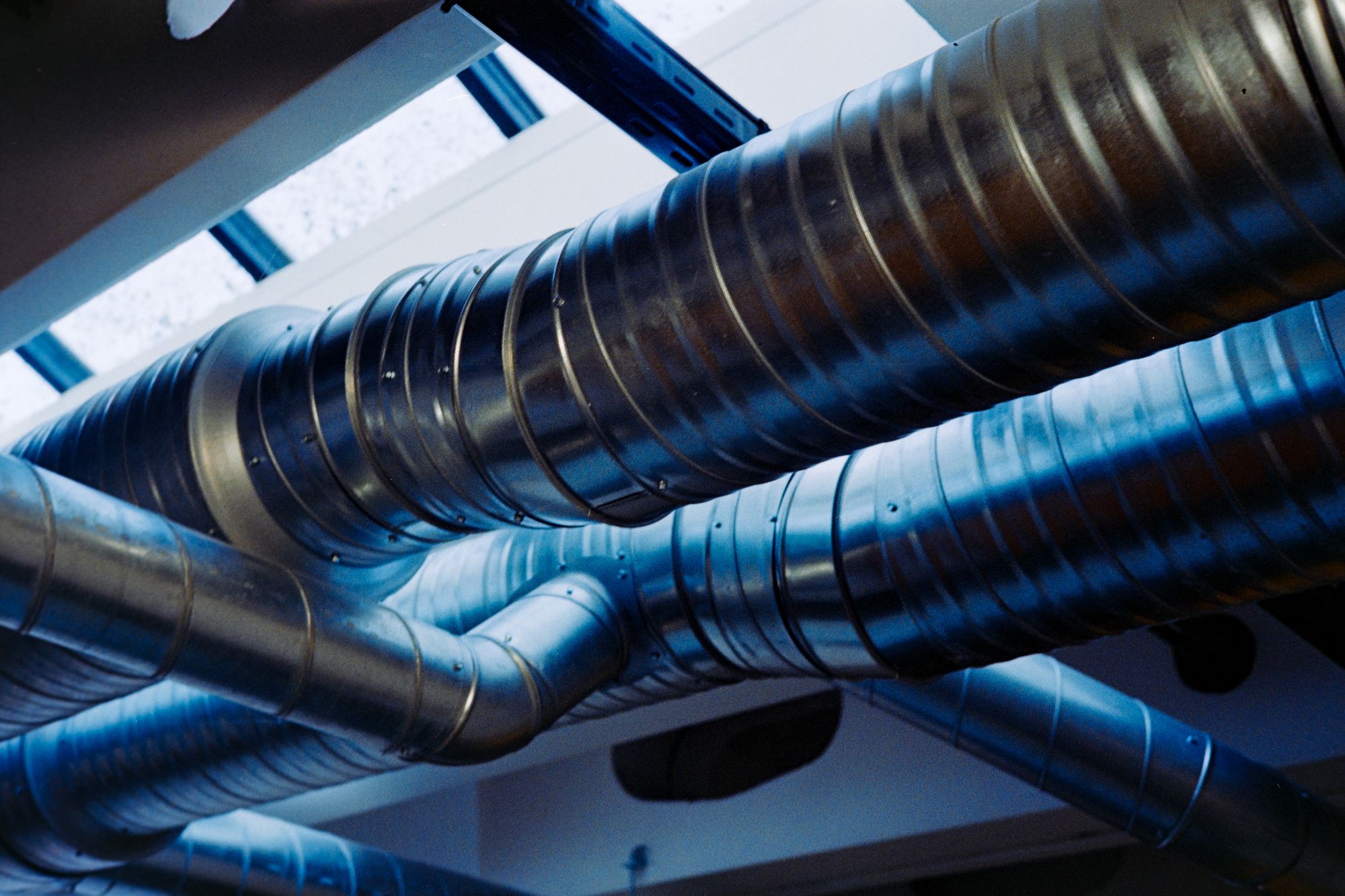 Galvanized steel ventilation ducts beneath an industrial ceiling